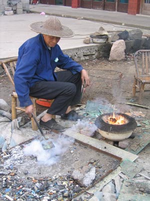 浙江溫嶺地區的電子垃圾拆解戶，為提取電腦線路板上的零件，用火烤將焊料熔化；圖片提供：賴芸